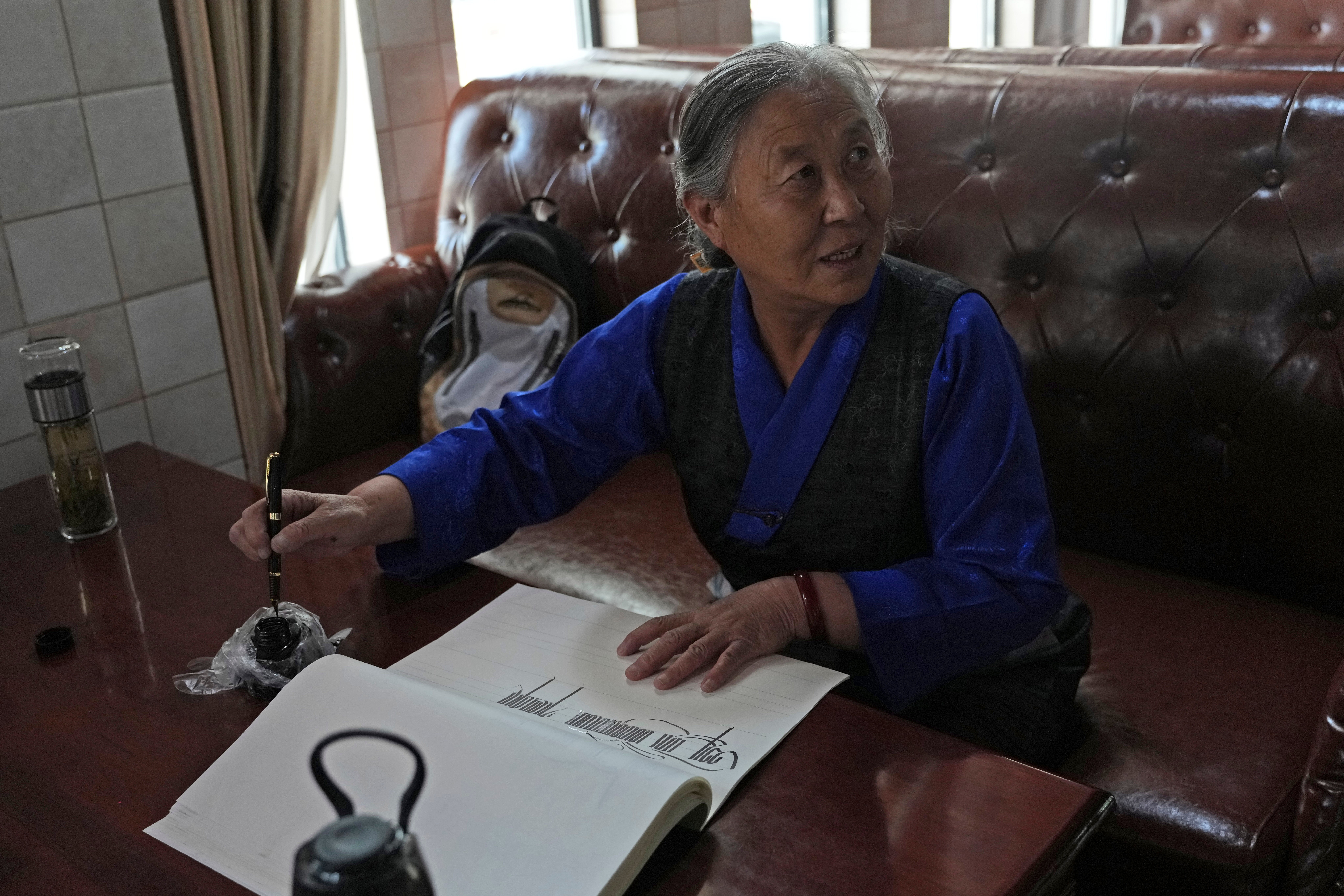 Kalsang Lhamo, a 73-year-old retired nurse, practices Tibetan calligraphy at the Chengguan District Day Care Center for the Elderly in western China